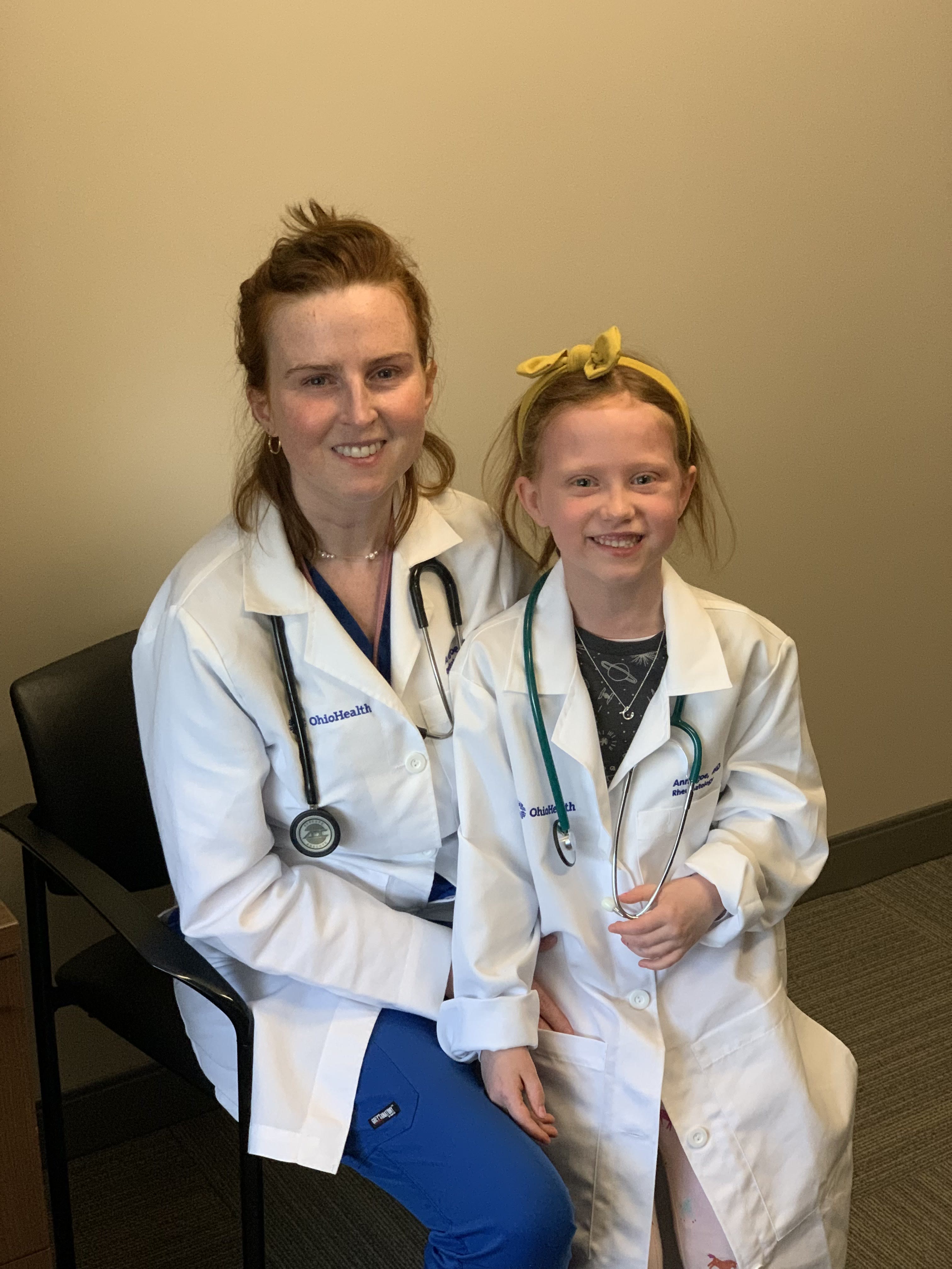 Ann Igoe, MD, beside a young guest wearing a white coat and stethoscope